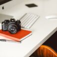 Nikon-kamera på en rød notatbok ved en datamaskin