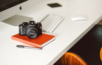 Nikon-kamera på en rød notatbok ved en datamaskin