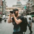 Fotograf tar bilder av mennesker og trafikk i en travel bygate
