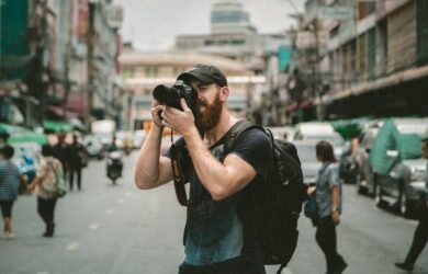 Fotograf tar bilder av mennesker og trafikk i en travel bygate